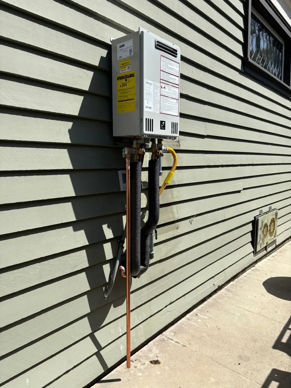 Outdoor tankless water heater mounted on exterior siding